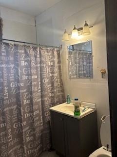 bathroom featuring toilet, a shower with shower curtain, and vanity