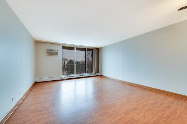 empty room featuring baseboard heating, wood finished floors, and baseboards