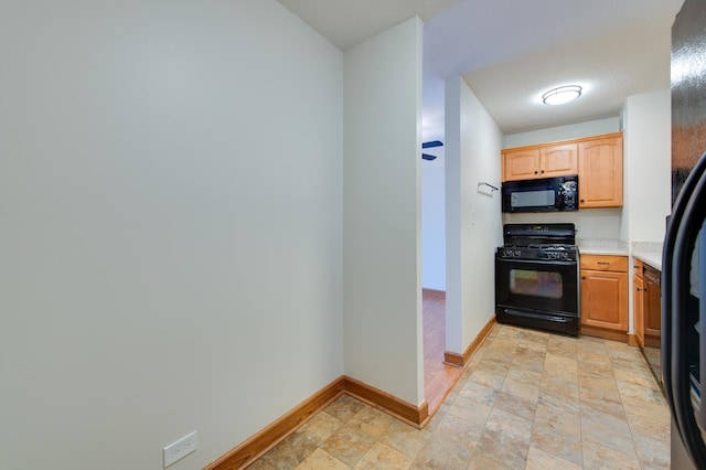 kitchen featuring baseboards, light countertops, and black appliances