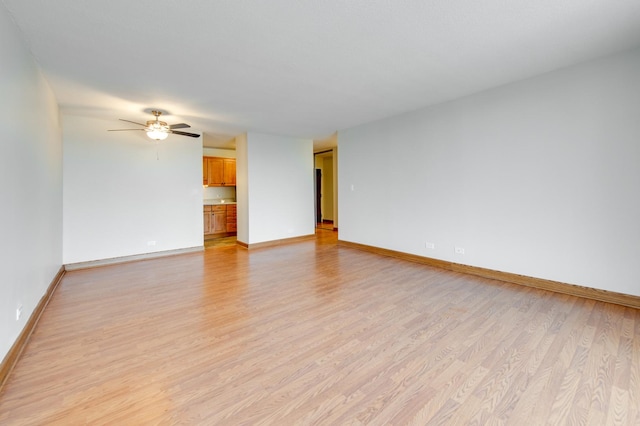 unfurnished living room with light wood-type flooring, a ceiling fan, and baseboards