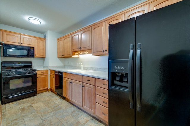 kitchen with light brown cabinets, black appliances, a sink, and light countertops