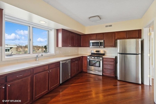 kitchen featuring tasteful backsplash, visible vents, appliances with stainless steel finishes, dark wood-type flooring, and a sink