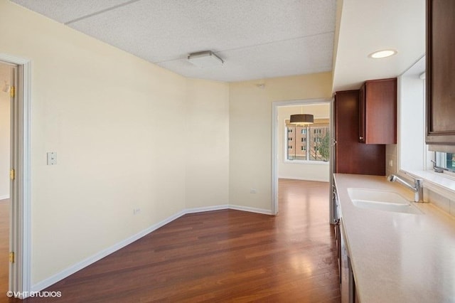 interior space with baseboards, dark wood-type flooring, light countertops, a textured ceiling, and a sink