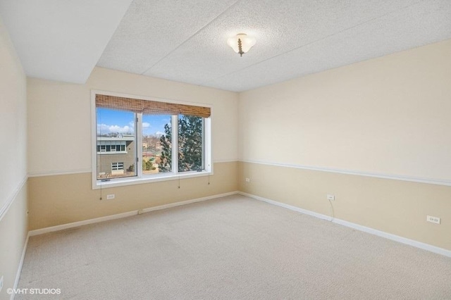 unfurnished room with carpet floors, baseboards, and a textured ceiling