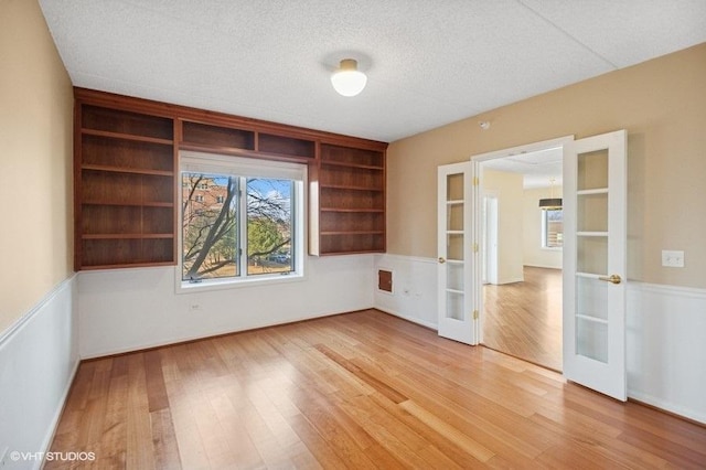 empty room featuring a textured ceiling, french doors, and wood finished floors