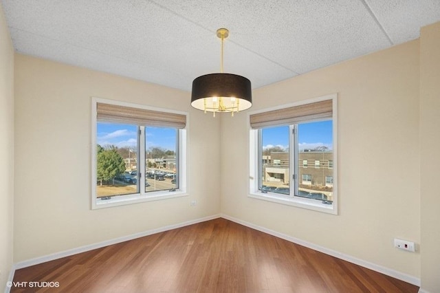 unfurnished room featuring a textured ceiling, baseboards, and wood finished floors