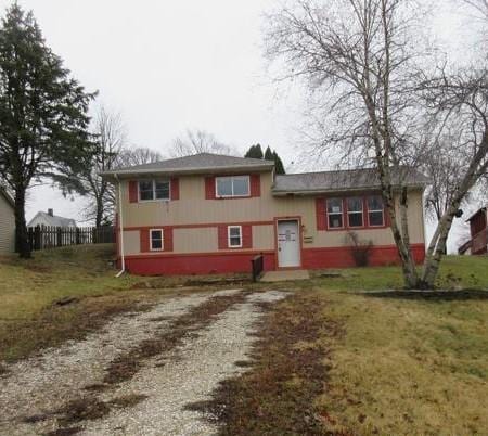 tri-level home with driveway, fence, and a front yard