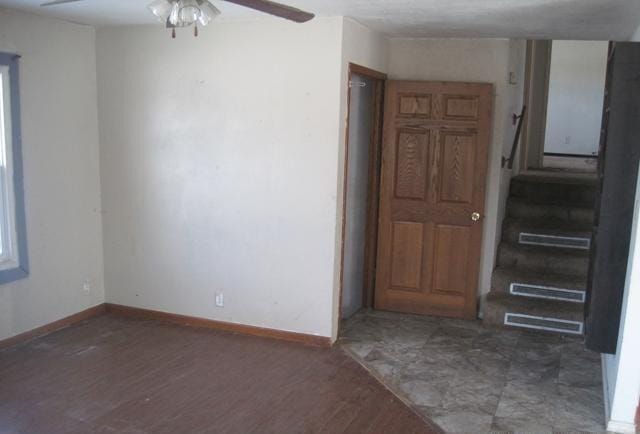 spare room featuring a ceiling fan, baseboards, and wood finished floors