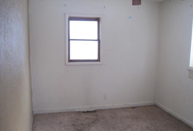 carpeted empty room featuring baseboards