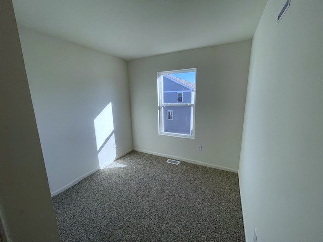 carpeted spare room featuring baseboards and visible vents