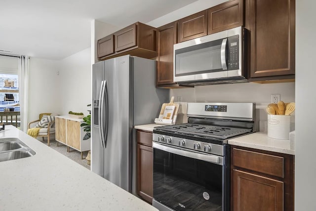 kitchen with appliances with stainless steel finishes, dark brown cabinets, and light stone countertops