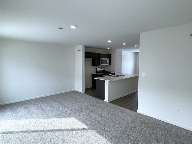 kitchen featuring stainless steel appliances, dark colored carpet, a sink, and baseboards