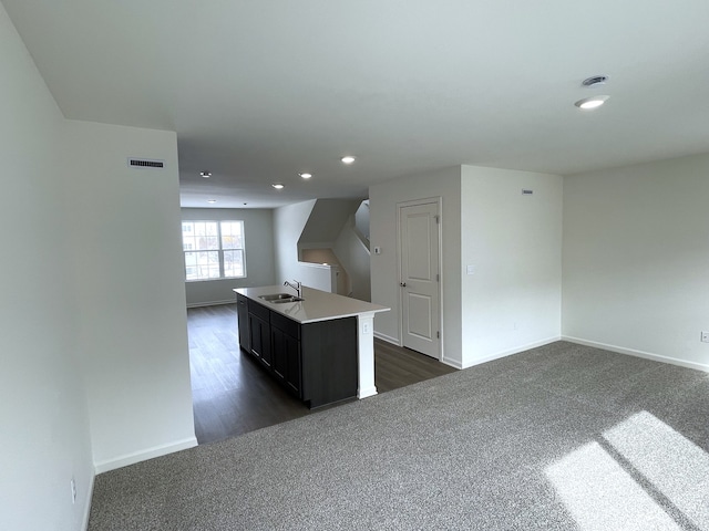 kitchen featuring recessed lighting, dark colored carpet, visible vents, open floor plan, and a sink