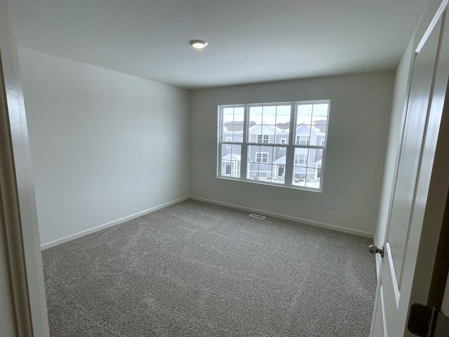 carpeted empty room with visible vents and baseboards