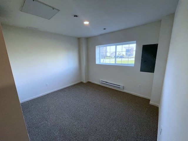 empty room featuring carpet floors, baseboards, and baseboard heating