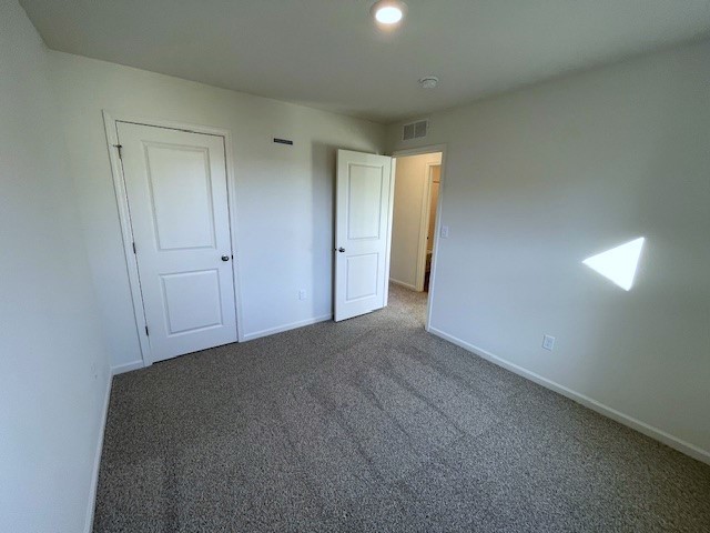 unfurnished bedroom with carpet, visible vents, and baseboards