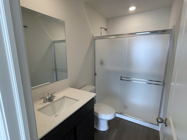 bathroom featuring recessed lighting, toilet, vanity, a shower stall, and wood finished floors