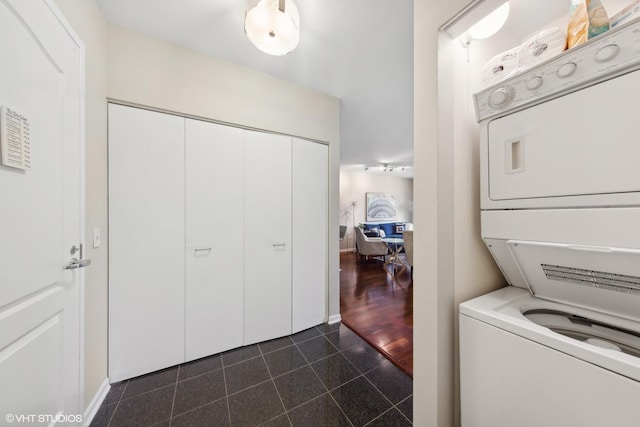 laundry room with stacked washer and dryer, granite finish floor, and baseboards