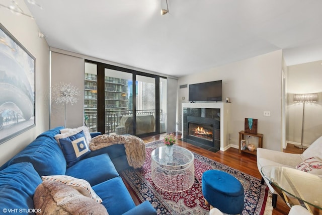 living area with floor to ceiling windows, a tile fireplace, wood finished floors, and baseboards