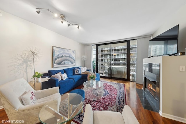 living area featuring wood finished floors, a glass covered fireplace, and baseboards