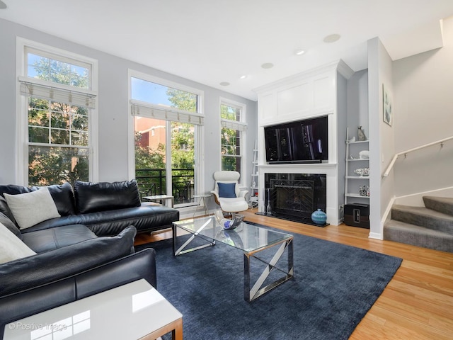 living area with stairway, baseboards, wood finished floors, and a high end fireplace