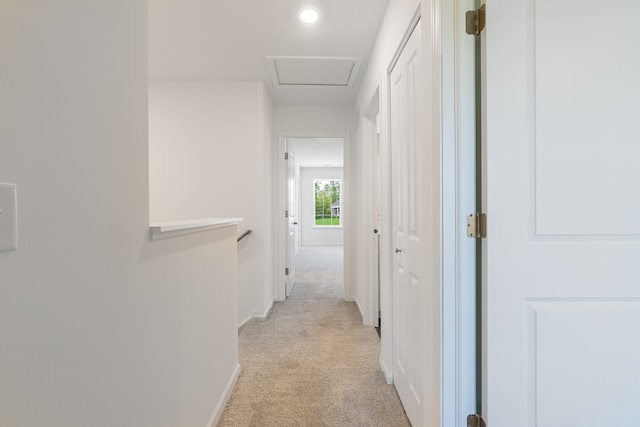 corridor featuring attic access, baseboards, light carpet, and an upstairs landing