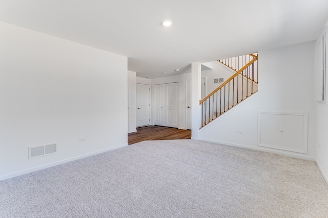 carpeted empty room featuring stairway, recessed lighting, visible vents, and baseboards