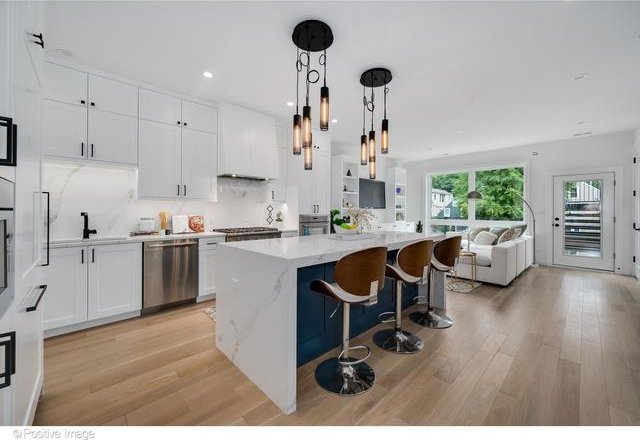 kitchen with appliances with stainless steel finishes, open floor plan, a sink, a kitchen island, and light wood-type flooring