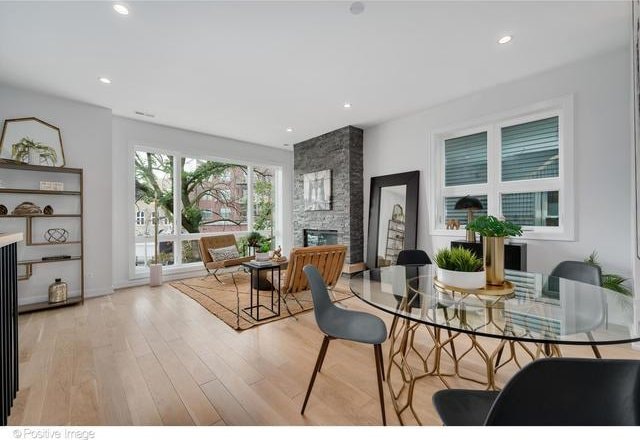 dining room with a large fireplace, wood finished floors, and recessed lighting