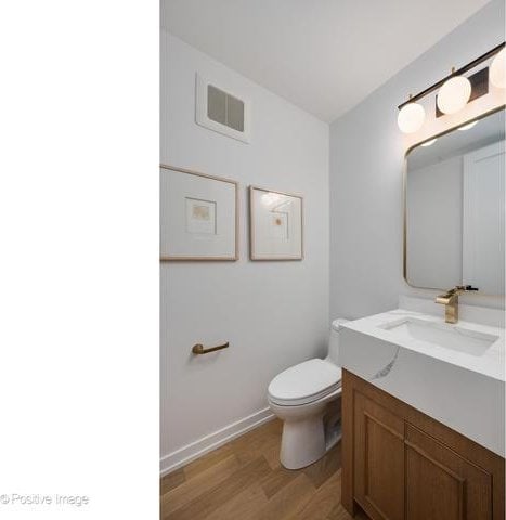 bathroom with toilet, visible vents, wood finished floors, and vanity