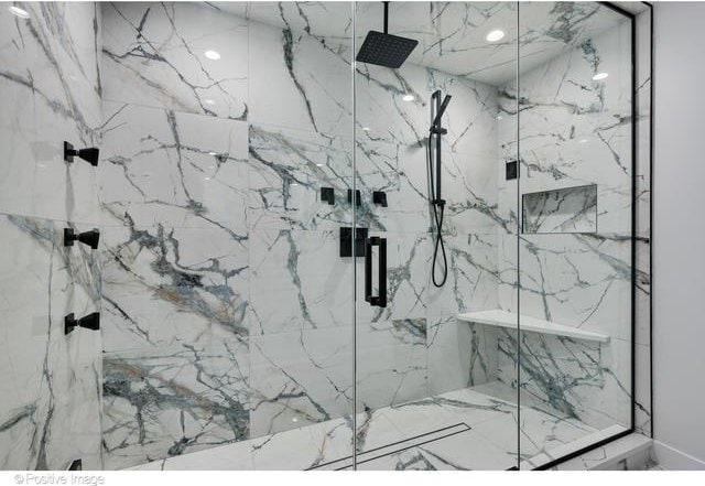 bathroom featuring a marble finish shower