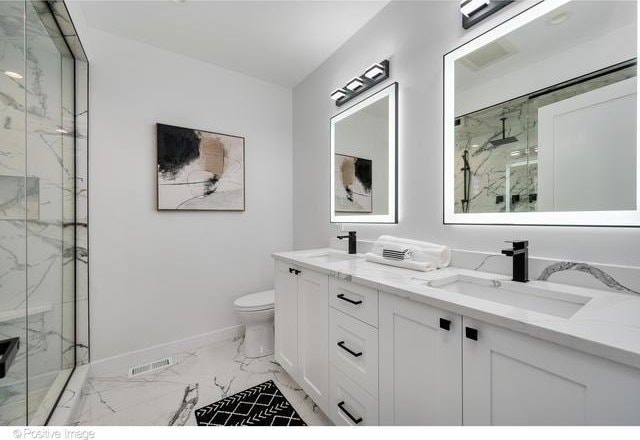 bathroom featuring marble finish floor, a sink, a marble finish shower, and toilet