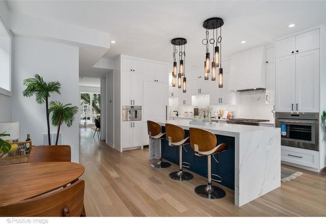 kitchen with light wood-style flooring, custom exhaust hood, oven, and white cabinetry