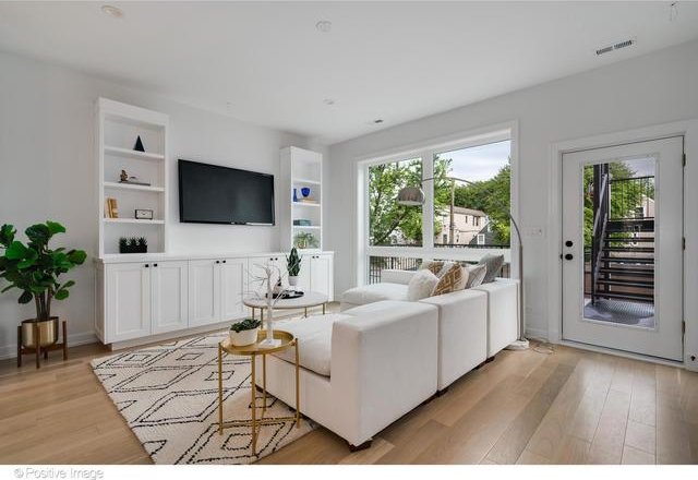 living area featuring a healthy amount of sunlight, light wood-style flooring, built in shelves, and visible vents