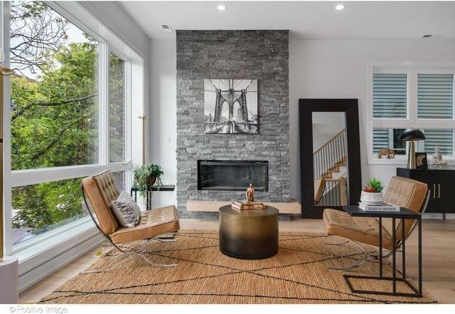 living area featuring a fireplace, stairway, wood finished floors, and recessed lighting