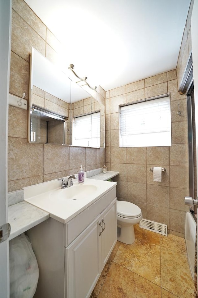 bathroom featuring tile walls, tasteful backsplash, visible vents, toilet, and vanity