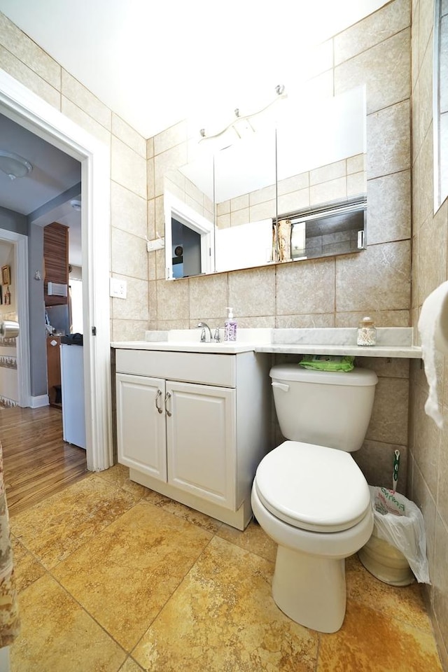 bathroom with toilet, backsplash, tile walls, and vanity