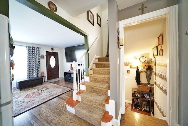 foyer entrance with stairs, wood finished floors, and baseboards