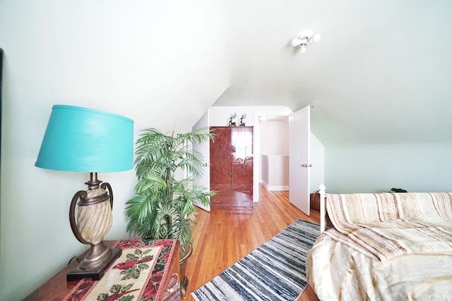 bedroom with light wood-type flooring and vaulted ceiling