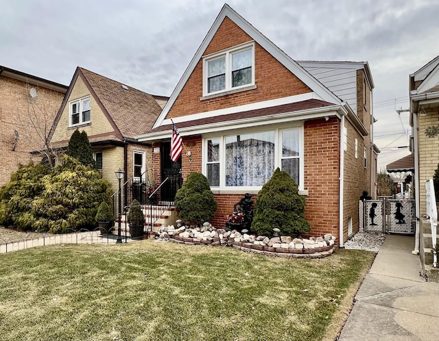 view of front of home with a front yard, a gate, fence, and brick siding