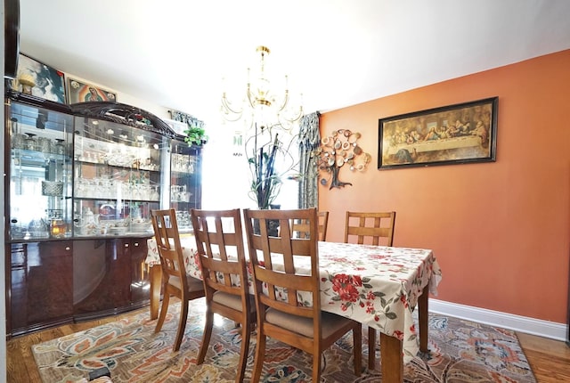 dining room with a chandelier, wood finished floors, and baseboards