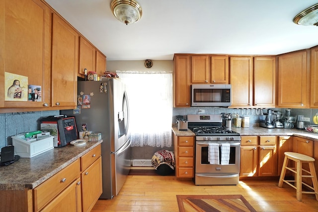 kitchen featuring appliances with stainless steel finishes, brown cabinetry, and light wood finished floors