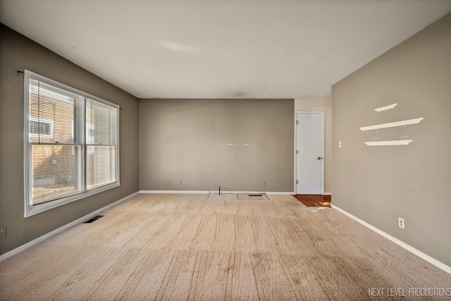 spare room with carpet, visible vents, and baseboards