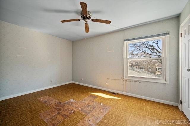 unfurnished room with wallpapered walls, ceiling fan, visible vents, and baseboards