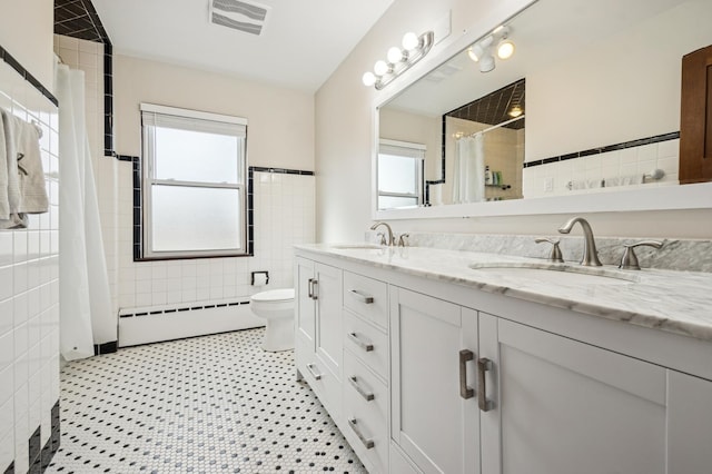 bathroom featuring tile walls, a baseboard radiator, visible vents, and a sink