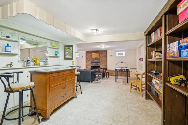 kitchen featuring a stone fireplace, a breakfast bar, open floor plan, light countertops, and brown cabinetry