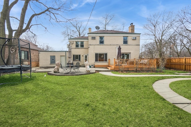 back of property featuring a patio, fence, a yard, a trampoline, and a chimney