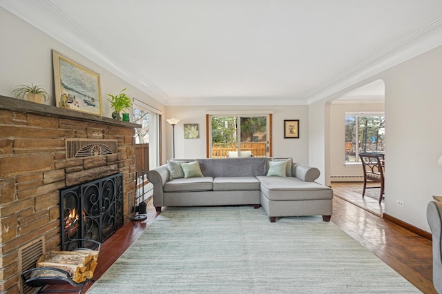 living room with ornamental molding, a wealth of natural light, a stone fireplace, and baseboards