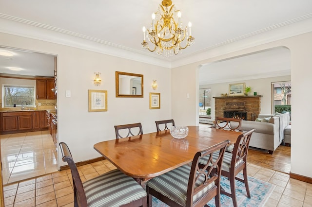 dining space with ornamental molding, a lit fireplace, baseboards, and light tile patterned floors