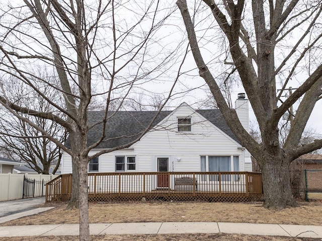 view of front of house with roof with shingles, a chimney, fence, and a wooden deck